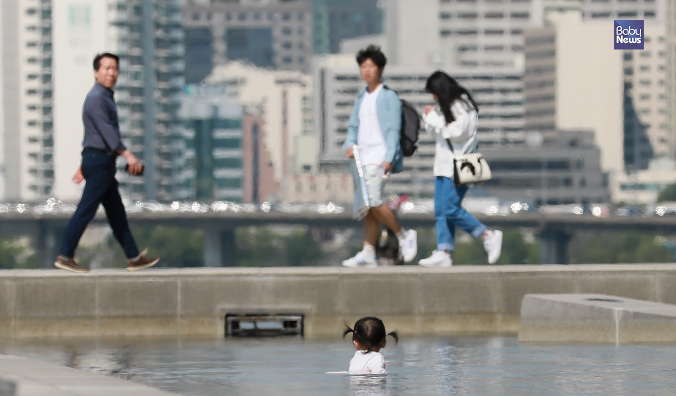 9일 오후 부모와 함께 서울 여의도 물빛광장을 찾은 한 꼬마 아이가 때이른 무더위를 피해 물놀이를 즐기자 지나는 시민들이 바라보고 있다. 최대성 기자 ⓒ베이비뉴스