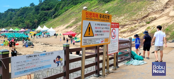 관광객들이 위험구역 및 준수사항이 명시된 표지판을 지나치고 있다. 물놀이를 포함한 해변활동을 할 때는 반드시 유의사항을 숙지해야 한다. ⓒ김재원