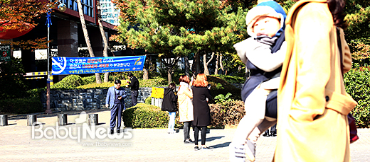 서울의 한 지하철역 주변 소공원 앞에서 시민들이 흡연을 하고 있는 가운데 한 엄마가 자녀를 품에 안고 지나가고 있다. 이기태 기자 ⓒ베이비뉴스