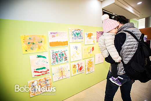 6일 오전 '모아모아 어린이 솜씨' 전시가 열리는 서울상상나라에서 한 아빠가 자녀를 품에 안고 음악을 들으며 음악을 색으로 표현한 작품들을 감상하고 있다. 이기태기자 ⓒ베이비뉴스
