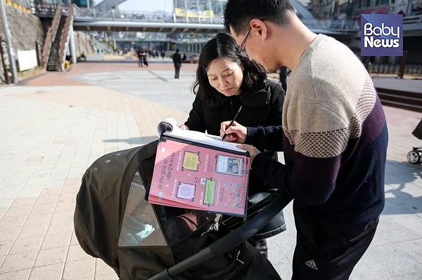11일 오후 서울 신림동 도림천 둔치에서 ‘관악구 마더센터 설치 조례제정 추진본부’가 서명운동을 벌였다. 유모차를 끌고 산책을 나온 한 시민이 서명에 참여하고 있다. 김재호 기자 ?베이비뉴스