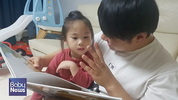 아이를 다리에 앉혀서 동화책을 읽어주는 모습 ⓒ황수웅