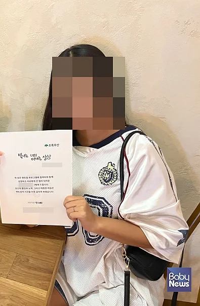 강미나(가명) 아동이 멘토링 프로그램 수료 후 수료증을 들고 기념촬영을 하고 있다. ⓒ초록우산
