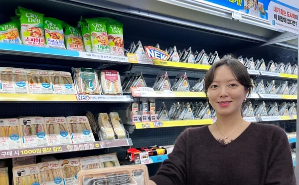 GS25에서 모델이 시장식 꼬마김밥과 화이트 데리야끼 치킨 샌드위치를 들고 포즈를 취하고 있다.