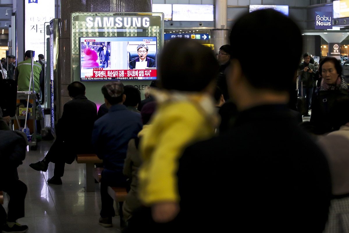 6일 오후 용산역에서 박근혜 전 대통령 1심 선고 TV생중계를 한 아이와 아버지가 지켜보고 있다. 김재호 기자 ⓒ베이비뉴스