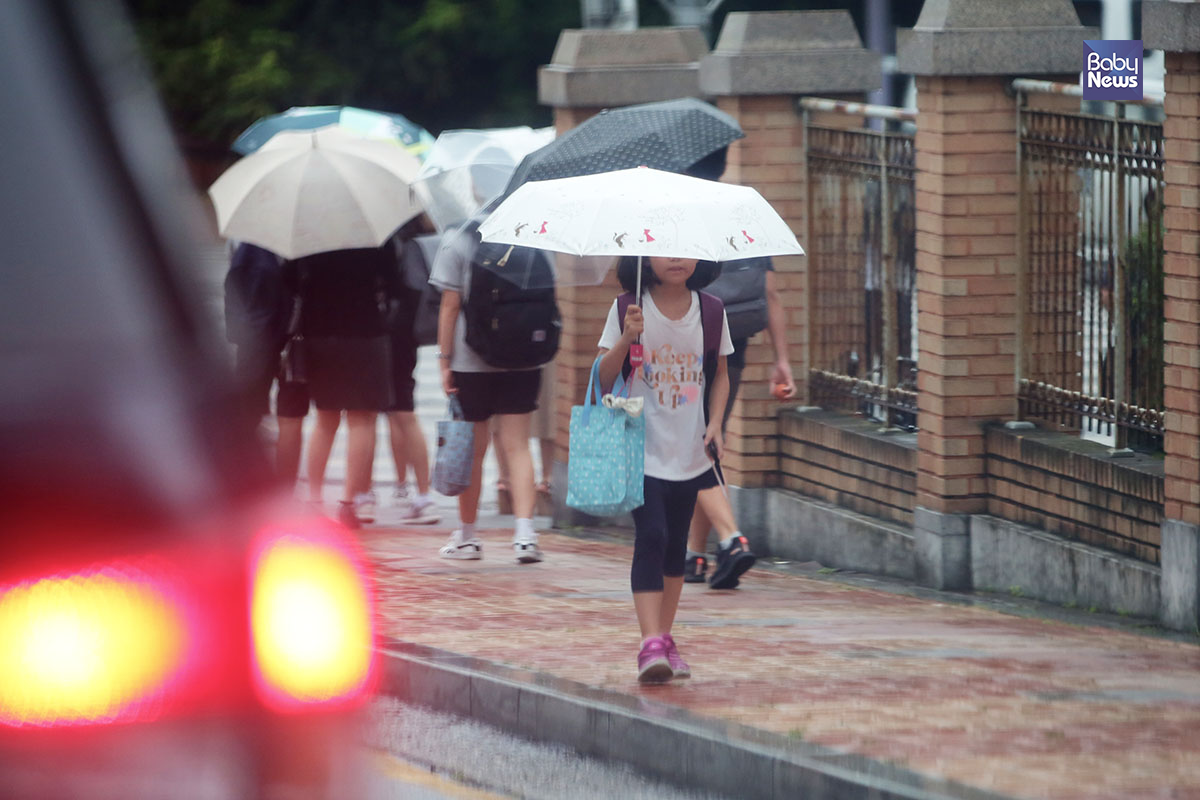 27일 아침 한 아이가 우산을 쓰고 쏟아지는 비를 피해 등교하고 있다. 김재호 기자 ⓒ베이비뉴스