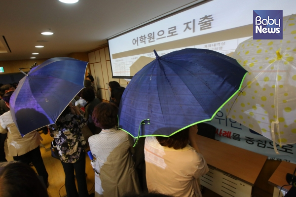 단상에서는 두 사람이 어두운 색 우산을 들고 프로젝터에서 나오는 화면을 막았다. 김재호 기자 ⓒ베이비뉴스
