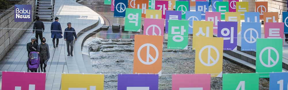 30일 서울 청계천에 설치된 '아름다운 선거 조형물' 아래로 유아차를 끌고 가는 부부가 보인다. 김재호 기자 ⓒ베이비뉴스