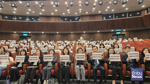 지난 11일 국회에서 열린 '성공적인 유보통합을 위한 교사 대 영유아 비율 개선 방안' 토론회. 참가자들이 '영유아 비율 개선부터'라고 쓰인 손피켓을 들고 있다. ⓒ서울시어린이집연합회